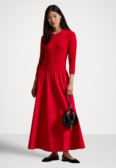 Rdeča obleka z zgornjim delom iz pletenine z vzorcem kabla in razširjenim krilom. Kombinirana s črno torbico in črnimi balerinkami. Gladek, mehak otip.