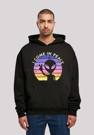 Black hoodie featuring a graphic design with an alien silhouette and the text "I COME IN PEACE," set against a striped gradient background.