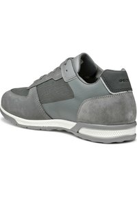 Scarpa atletica grigia caratterizzata da una combinazione di materiali lisci e testurizzati, pannelli in rete e suola in gomma bianca. Marchio Geox sul tallone.