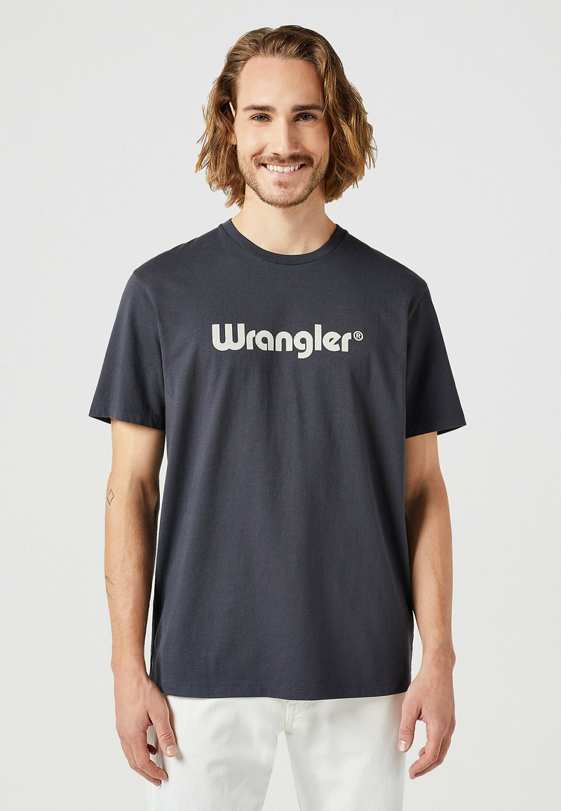 Mörk marinblå bomull T-shirt med en framträdande vit "Wrangler"-logotyp över bröstet, korta ärmar och rundad halsringning.