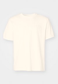 Krämfärgad T-shirt med korta ärmar i bomull. Har ett präglat "Timberland"-logotyp och trä grafik på framsidan. Standard rundhalsad design.