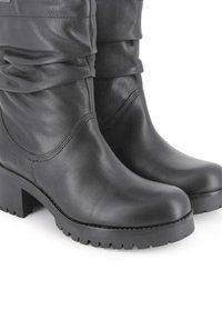 Botas de tobillo de cuero negro con un diseño arrugado, tacón grueso y suela de goma con ranuras texturizadas para mayor tracción.