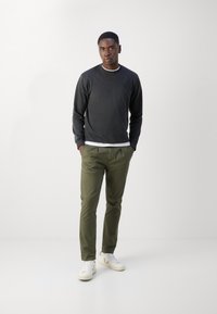 Hanorac gri cu guler rib, asociat cu pantaloni chinos de culoare verde măsliniu și adidași albi. Design simplu, fără modele.