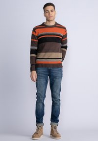 Gestreepte trui in oranje, bruin en zwart, met geribbelde manchetten en zoom. G gedragen bij blauwe jeans en beige hoge laarzen.