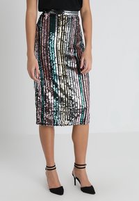 Jupe crayon en sequins avec des rayures verticales dans les couleurs : rose, bleu-vert, argent et noir. Longueur mi-mollet avec une silhouette ajustée.