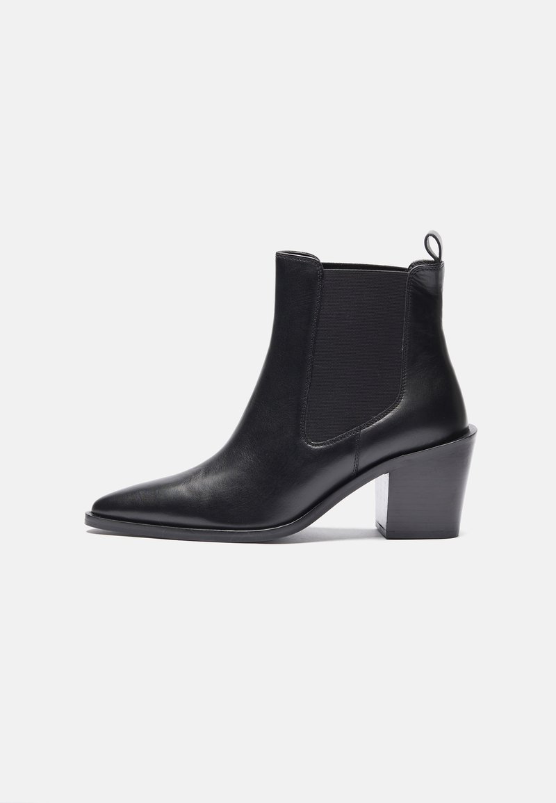 Bottine en cuir noir avec bout pointu, panneau latéral élastique, languette au talon et talon bloc haut sur fond blanc.