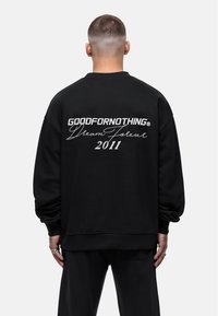 Felpa nera con un audace logo ricamato bianco e la scritta "GOODFORNOTHING Dream Forever 2011" sul retro.