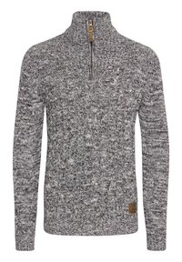 Pull en maille chinée gris et blanc avec col montant, fermeture éclair à l'avant, motif en maille torsadée et une petite étiquette en cuir marron avec logo près de l'ourlet.