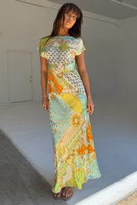 Hosszú nyári ruha könnyű anyagból, élénk aqua, narancs és sárga színekben, díszítő grafikákkal és laza szabással.