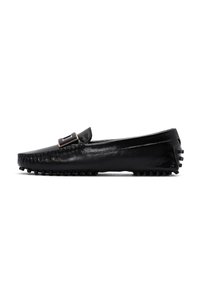 Mocassins en cuir noir avec une semelle plate, dotés d'une boucle décorative et de coutures visibles sur le dessus. Semelle extérieure avec une texture antidérapante.