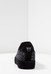 Svart tygsko med en texturerad flerfärgad ovandel, en snygg design och en logotyp på hälen, samt en vadderad sula.