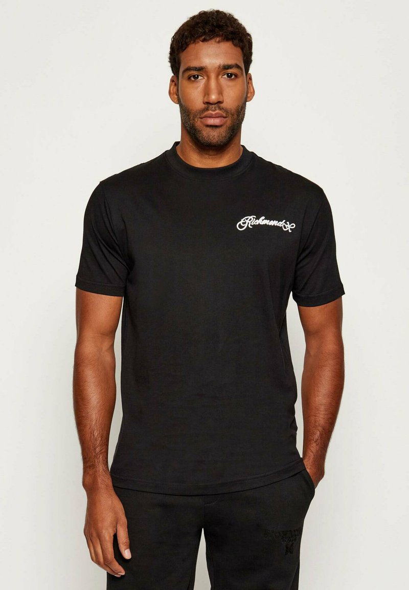T-shirt in cotone nero con maniche corte e collo a giro, con logo scritto in bianco sulla parte sinistra del petto. Tessuto liscio e design aderente.