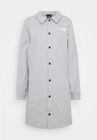 Abrigo impermeable gris claro con cierre frontal de botones, cuello, puños elásticos y logotipo en el pecho. Textura suave y diseño hasta las rodillas.