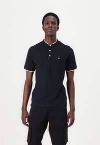 Marineblauwe polo shirt van katoen met een kraag, drieknoopsluiting en witte accenten op de kraag en de mouwen. Klein logo op de borst.