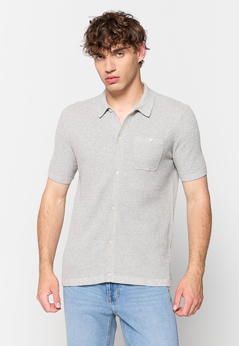 Grijze poloshirt met korte mouwen, voorzien van een gestructureerd patroon, knoopsluiting en een borstzak. Heeft een puntige kraag en rechte zoom.