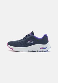 Dark blue mesh sneaker with purple accents, white cushioned sole, and a prominent logo. Features laces and a textured upper for breathability.