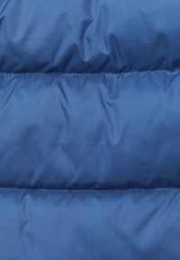 Blaues Pufferjackenmaterial mit glatter Textur, das über gesteppte Abschnitte und horizontale Nähte verfügt, um Isolierung und Wärme zu bieten.