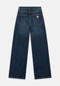 Jeans i mörkblått denim med vida ben, med två bakfickor och en triangulär logotypdetalj på höger ficka.
