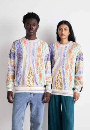 Pullover in Pastellfarben mit aufwendigen Mustern, langen Ärmeln, gerippten Bündchen und Rundhalsausschnitt, kombiniert mit Jeans und weitem Hosen.