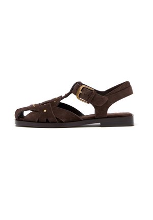 Mørkebrun ruskind åben-tå flad sandal med T-rem design, guldspænde og små dekorative nitter på sidestrapper.