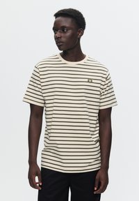 Tricou scurt cu mâneci, în dungi, de culoare bej și verde măsliniu, având un decolteu rotund și un mic logo brodat pe piept. Textură de țesătură netedă.