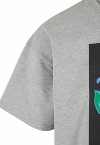 Camiseta de algodón gris con manga corta y un vibrante estampado gráfico en verde y azul sobre un fondo negro.