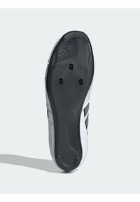 Sole cyklistické obuvi se třemi body pro připevnění klipsů, černé gripové podložky na patě a špičce, a bílý svršek s černými pruhy.