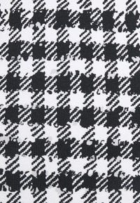 Svartvit hounds tooth-mönster med texturerade linjer och former, som framträdande visar växelvis solida och konturerade områden i varierande täthet.