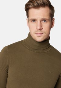 Zielona oliwkowa sweter z golfem wykonany z prążkowanego materiału; dopasowany fason z obcisłym kołnierzem i subtelnym logo na piersi.