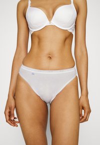Sous-vêtements blancs en coton doux, coupe hipster taille mi-haute, avec un délicat biais en dentelle le long de la taille et des ouvertures des jambes.