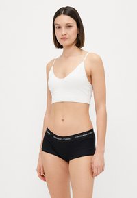 Sorte bomulls boyshorts med en logo-bredde, sammen med en hvit bomulls bralette med tynne stropper og v-utforming.