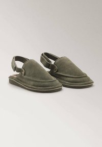 Green suede slingback shoes with a rounded shape, textured surface, and a cushioned footbed, featuring a button detail on the side.