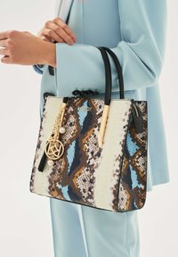 Raštuota nešioklė su mėlynos, rudos ir kreminės spalvų gyvatės odos raštu, su juodais odiniais rankenomis ir aukso spalvos metalo detalėmis.