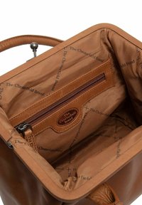 Interno di una borsa in pelle color tan che presenta una tasca con zip e fodera con motivo a logo. Texture liscia con forma strutturata e manico arrotondato.
