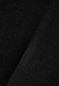 Black textured fabric with a slightly brushed surface, folded at an angle, showcasing its depth and richness.