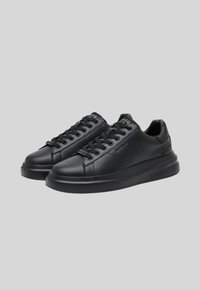 Baskets en cuir noir avec une finition lisse, bout rond et lacets. Dotées d'une épaisse semelle en caoutchouc noir et d'un branding subtil.