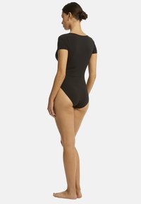 Body nero a maniche corte con design a gamba alta e texture liscia, mostrato da dietro, che rivela una silhouette aderente.