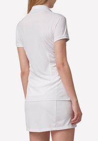 Biała koszulka polo z krótkim rękawem i kołnierzykiem, w połączeniu z pasującą białą spódnicą. Gładki materiał o dopasowanym kroju i czystych liniach.
