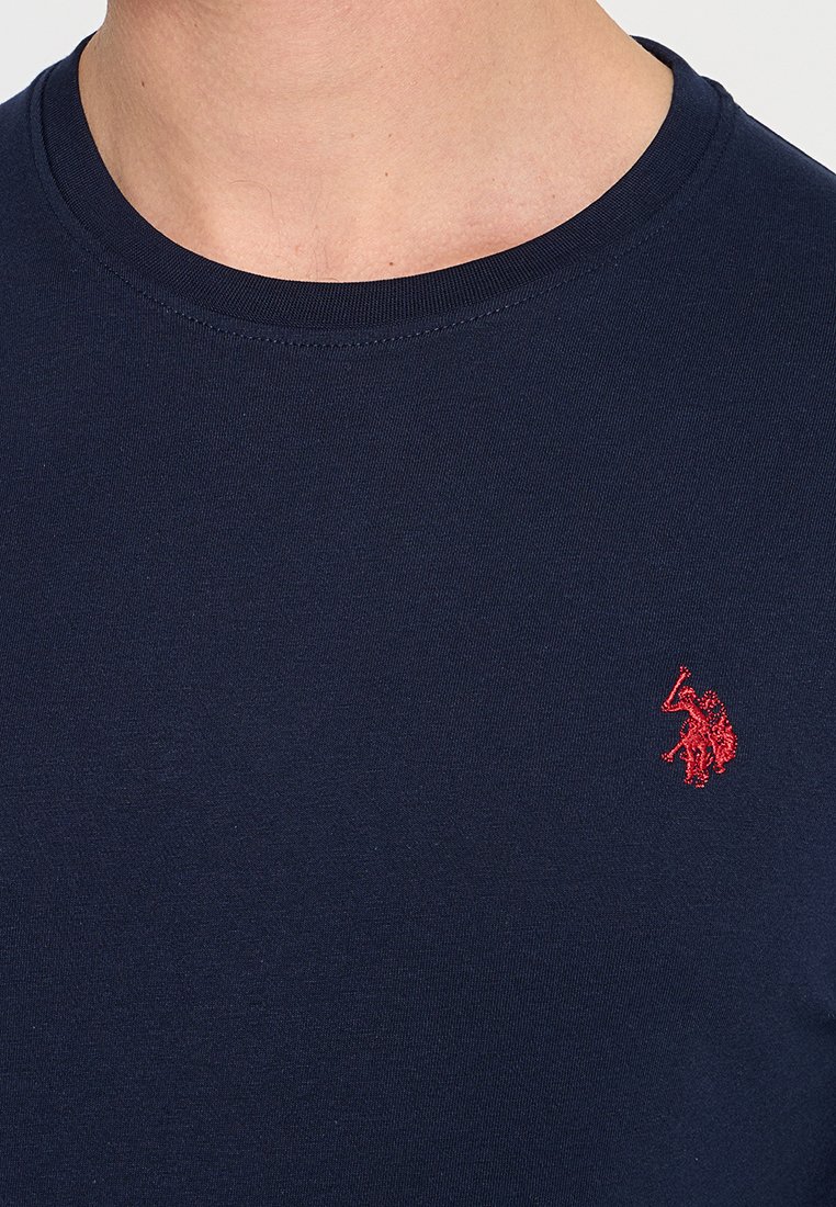 Navy-blaue Baumwoll-T-Shirt mit Rundhalsausschnitt, das ein kleines rotes gesticktes Logo auf der linken Brust zeigt. Weiche, glatte Textur mit taillierter Form.