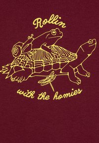 Μαρουλίνιο ύφασμα με κίτρινο σχέδιο που απεικονίζει μια χελώνα, δύο βάτραχοι, μια σαλιγκάρι και μια λιβελούλα, μαζί με το κείμενο "Rollin' with the homies."