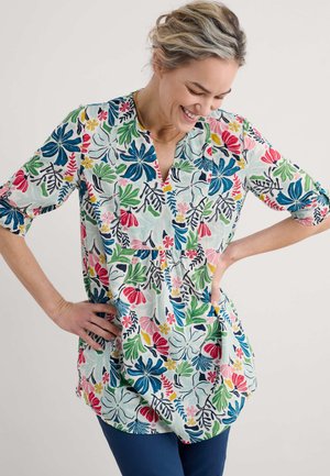 Patroon tuniek in een lichte stof met een veelkleurige bloemenprint in blauw, groen, rood en roze. V-hals en driekwartmouwen.