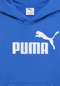Μπλε φούτερ με κουκούλα με λευκό λογότυπο Puma και κείμενο στο στήθος, καθώς και ορατή ετικέτα μεγέθους μέσα στο γιακά.