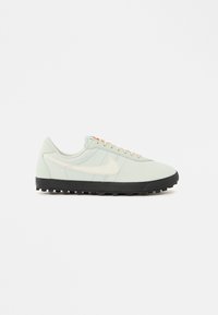 Αθλητικό παπούτσι ανοιχτού πράσινου χρώματος με λείο επάνω μέρος, μπεζ λεπτομέρειες, μαύρη καουτσούκ σόλα και πορτοκαλί οπή κορδονιών. Διαθέτει κλασική σιλουέτα και κορδόνια.