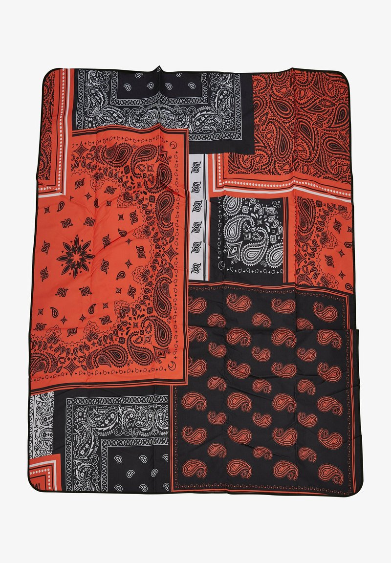 Pikšanas segas, kas rotātas ar melnu un sarkanu bandanu dizainu, ar paisley rakstiem, gludu tekstūru un kontrastējošiem baltajiem akcentiem.