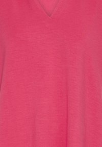Tissu rose vif à encolure en V avec une texture douce et lisse, probablement une partie d'un vêtement tel qu'une chemise ou une robe.