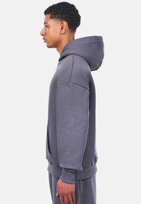 Grauer Kapuzenpullover mit entspannter Passform, gerippten Bündchen und Kängurutaschen, aus weichem Baumwollmischgewebe.