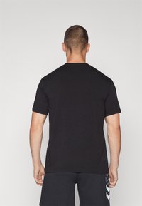 Musta lyhythihainen T-paita pyöreällä kaula-aukolla, valmistettu pehmeästä kankaasta, joka tarjoaa sileän pinnan ja rentoa istuvuutta.