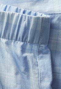 Helles blaues Gewebe mit einer weichen Textur verfügt über einen gerafften Taillenbund und ein dezentes Karomuster, das ein leichtes und atmungsaktives Design betont.