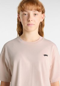 Ljusrosa kortärmad t-shirt gjord av mjuk bomull, med en liten svart skateboardgrafik på vänster bröstområde.