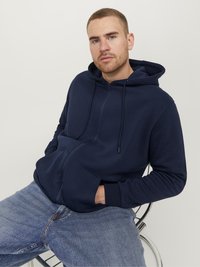 Marine zip-up hoodie gemaakt van zachte stof, met een vo zak, verstelbare trekkoordcapuchon en ribgebreide manchetten. Gecombineerd met lichtblauwe jeans.